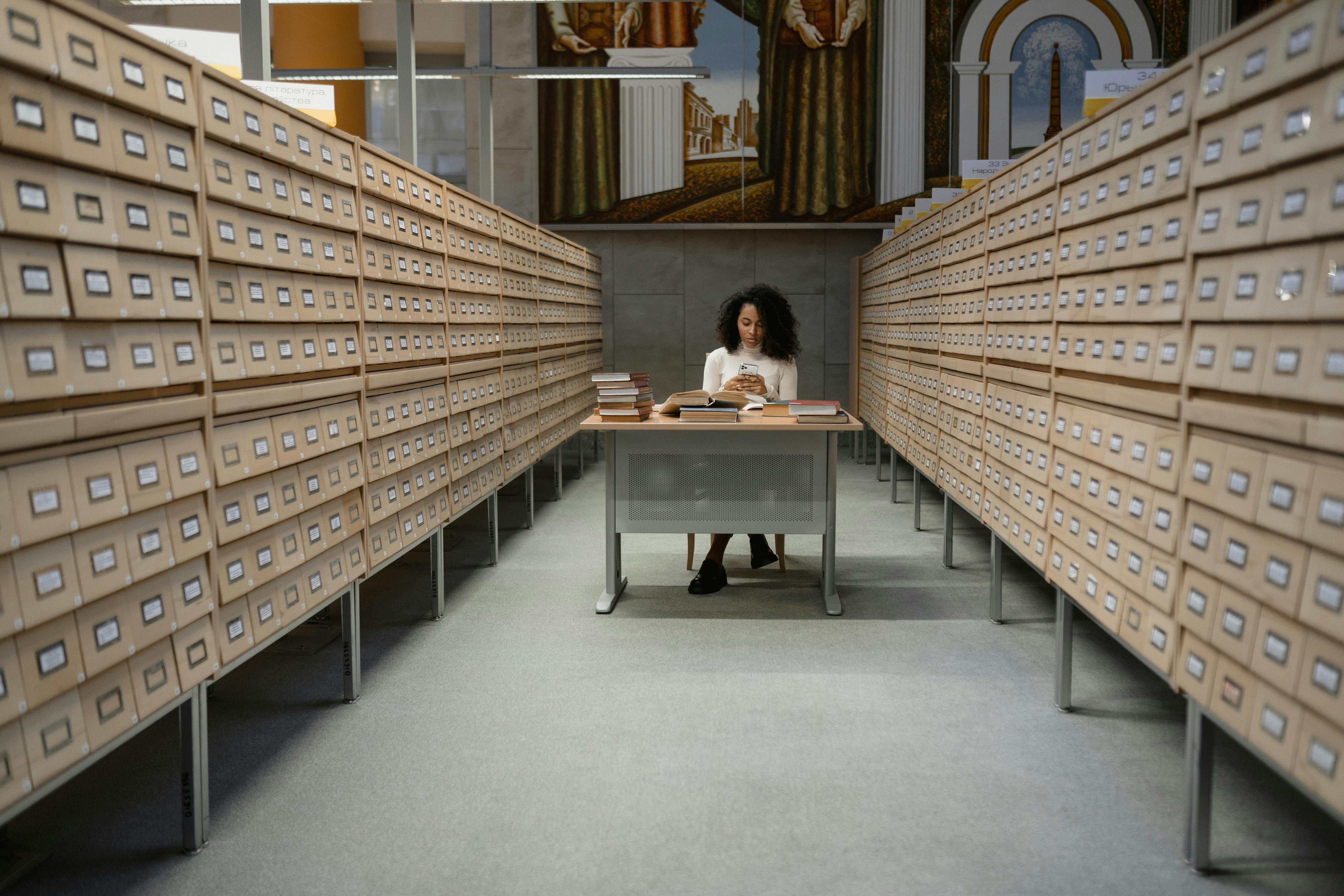 a person sitting by a table between two filing cabinets